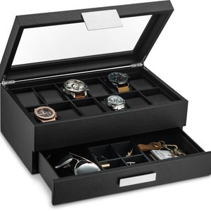 May include: Black leather watch box with a glass top and a pull-out drawer. The top compartment has 12 slots for watches and the drawer has compartments for other accessories.