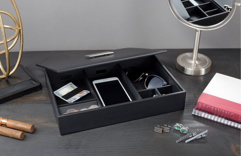 May include: Black leather valet tray with compartments for organizing items like a phone, sunglasses, and cash. The tray is open and has a silver metal handle.