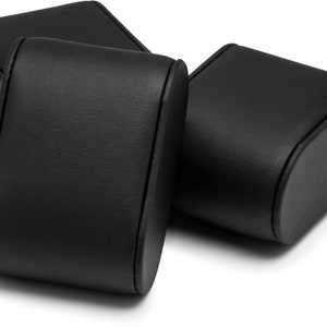 May include: Three black leather watch boxes with a rounded shape. The boxes are designed to hold and display watches.