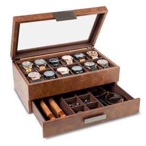 May include: A brown leather watch box with a glass top, displaying twelve watches. The bottom drawer is open, revealing cigars, sunglasses, and small compartments for accessories. The box has a rectangular shape and a metal handle.