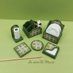 Pode incluir: Um conjunto de cozinha em miniatura verde com detalhes de azulejos coloridos. O conjunto inclui um porta-toalhas de papel, um porta-utensílios, um suporte para pratos, bases para copos e um porta-guardanapos. Talheres e pratos brancos incluídos.