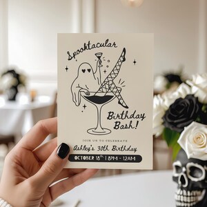 Może przedstawiać: Kremowe zaproszenie urodzinowe z czarną ilustracją ducha w kieliszku do martini, z napisem "Spooktacular Birthday Bash!". Na zaproszeniu widnieje napis "Ashley's 30th Birthday" oraz data i godzina.