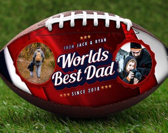 May include: A brown leather football with white laces and a red and white design. The design includes the text "Worlds Best Dad" and two circular photo inserts. The text "FROM JACK & RYAN" and "SINCE 2018" are also included.