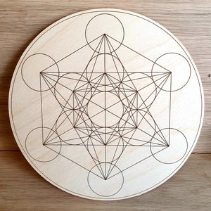 May include: A wooden circle with a geometric design of a star with overlapping circles and lines. The design is brown and the circle is light wood.
