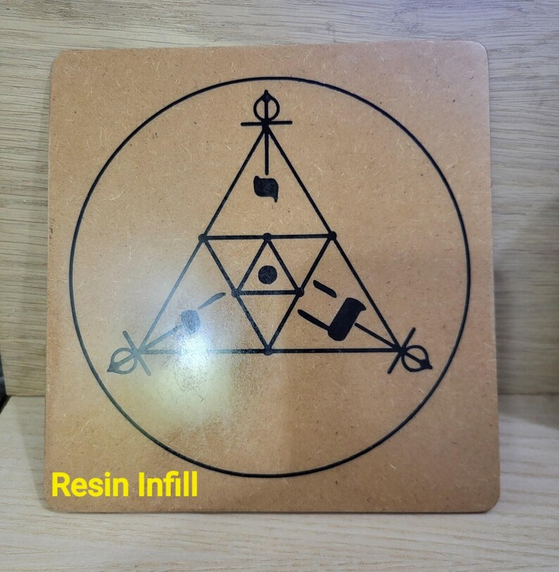May include: Square wooden coaster with a geometric design in black, featuring a triangle within a circle. The text "Resin Infill" is printed in yellow at the bottom. The coaster is a light brown color.