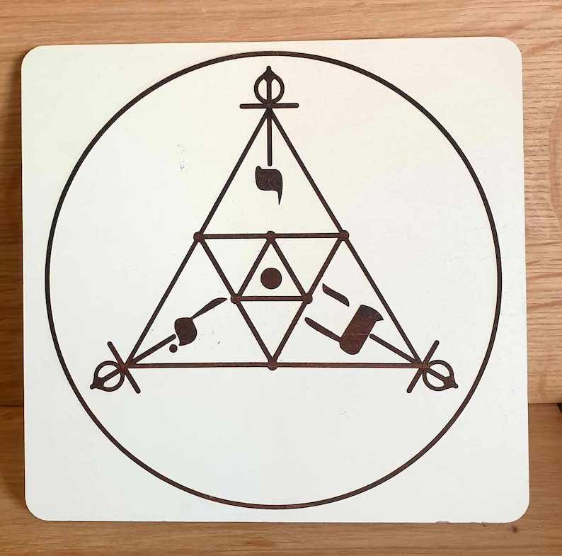 May include: A square, off-white wooden plaque featuring a brown geometric design. The design includes a circle, a triangle, and various symbols. The plaque has rounded corners and is set against a wooden surface.