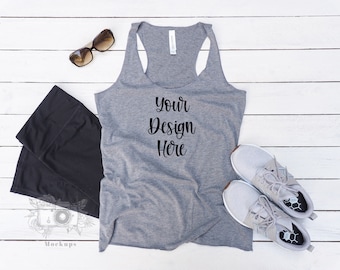 May include: A gray tank top with the text "Your Design Here" is displayed with black leggings, gray athletic shoes, and sunglasses. The items are arranged on a white wooden surface, creating a lifestyle product shot.