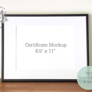 May include: A black frame mockup with a white mat and a white background. The frame is 8.5 inches by 11 inches and is sitting on a wooden surface. The text "Certificate Mockup" and "8.5" x 11" is printed in black on the white mat. The text "PSD Smart Object & Jpeg" is printed in black on a light green circle in the lower right corner of the image.