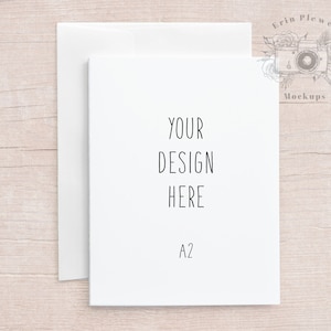 Pode incluir: Mockup de cartão branco com o texto "YOUR DESIGN HERE" e "A2" impresso nele. O cartão está sobre uma superfície de madeira clara.