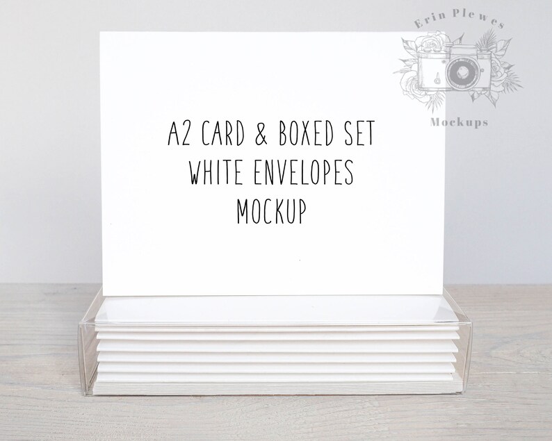 May include: A white card and envelope set mockup. The card is blank and the envelopes are stacked in a clear plastic box. The text on the card reads "A2 Card & Boxed Set White Envelopes Mockup".