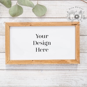 Pode incluir: Uma moldura de madeira com fundo branco e o texto "Your Design Here" sobre um fundo de madeira branqueada.