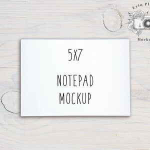 Op de afbeelding: Witte notitieblok mockup met de tekst "5x7 Notepad Mockup" op een witte houten achtergrond.