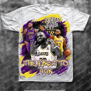May include: White t-shirt with a purple and yellow design featuring LeBron James in a Los Angeles Lakers jersey. The text "LeBron James" and "The First to 40K" are printed on the shirt.