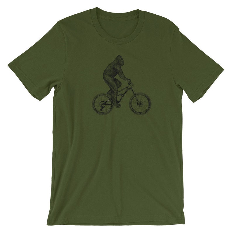 Puede incluir: Una camiseta verde con una ilustraci&oacute;n en blanco y negro de un gorila montando una bicicleta de monta&ntilde;a.