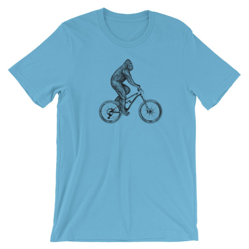 Puede incluir: Una camiseta azul claro con una ilustraci&oacute;n en blanco y negro de un gorila montando una bicicleta de monta&ntilde;a.