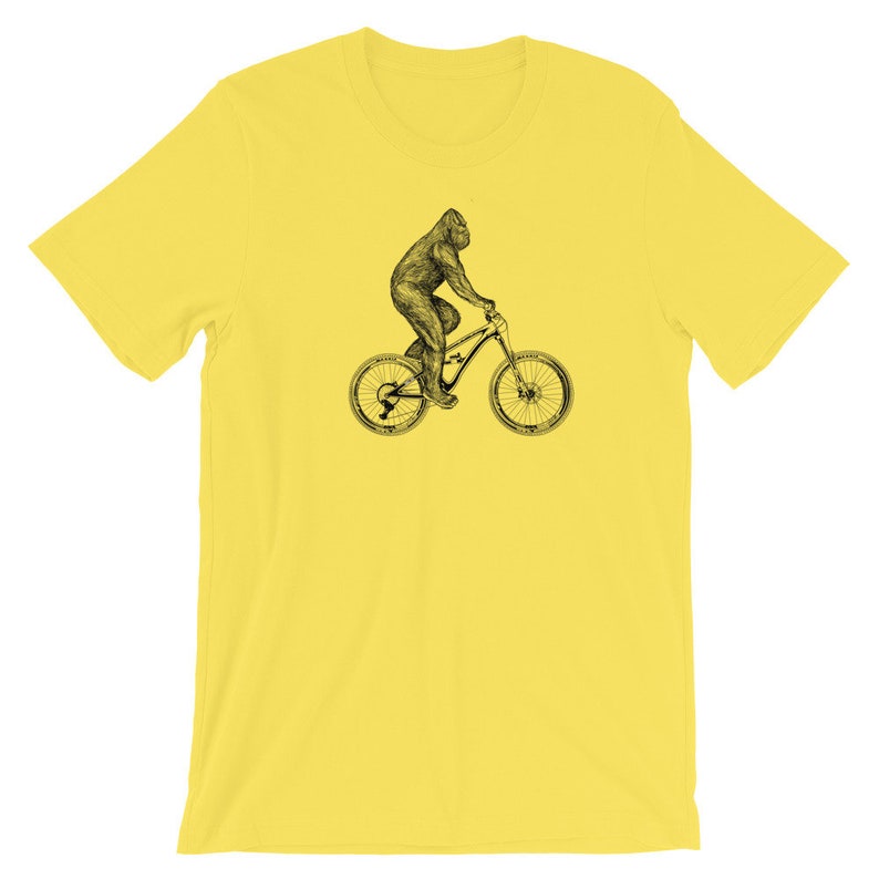 Puede incluir: Una camiseta amarilla con una ilustraci&oacute;n en blanco y negro de un gorila montando una bicicleta de monta&ntilde;a.
