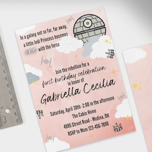 Puede incluir: Invitación rosa y blanca con temática de Star Wars. La invitación presenta una Estrella de la Muerte y un Halcón Milenario. El texto dice "Únete a la rebelión para una celebración de primer cumpleaños en honor a Gabriella Cecilia".