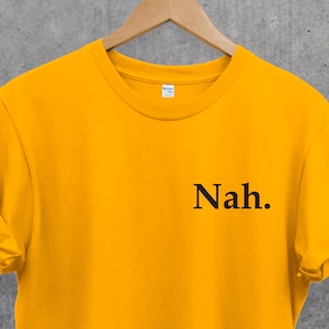 Peut inclure: Un t-shirt jaune avec le mot "Nah." imprimé en noir sur le devant.