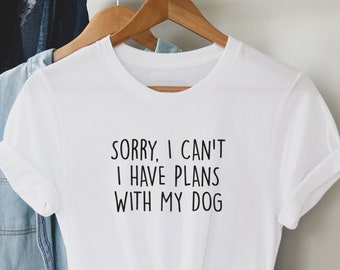 May include: White t-shirt with the text "Sorry, I can't I have plans with my dog" printed in black.
