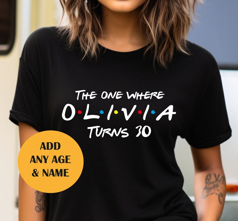 May include: Black t-shirt with white text that reads "The One Where Olivia Turns 30". The text is styled like the popular TV show "Friends".