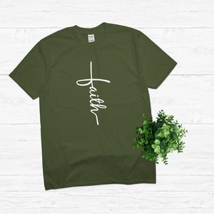 Puede incluir: Una camiseta verde con una cruz blanca y la palabra "faith" escrita verticalmente en ella.