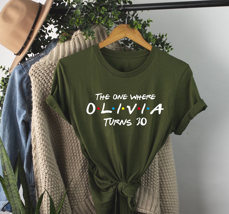 May include: Green t-shirt with the text "The One Where Olivia Turns 30" in white with colorful dots. The shirt is tied in a knot at the bottom.