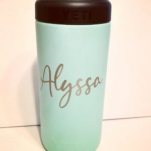May include: A light blue Yeti Rambler with a black lid and the name "Alyssa" written in gold lettering.