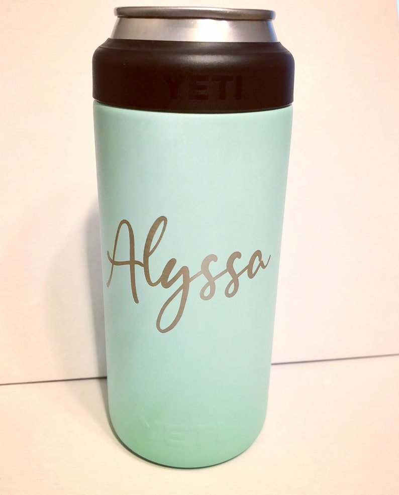 May include: A light blue Yeti Rambler with a black lid and the name "Alyssa" written in gold lettering.