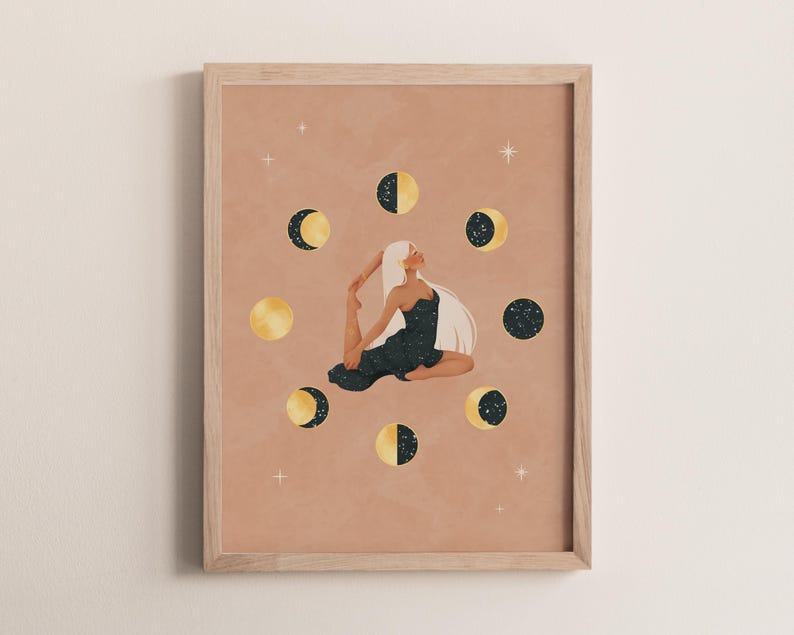 May include: A framed art print featuring a woman in a yoga pose surrounded by phases of the moon. The artwork has a warm, neutral background with gold and navy blue accents. The woman has long white hair and is wearing a dark dress.