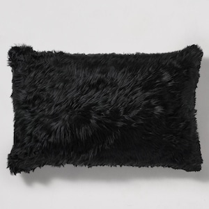 May include: A black faux fur throw pillow. The pillow is rectangular and has a soft, fluffy texture.
