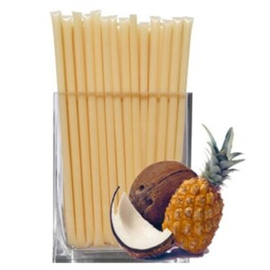 May include: A clear glass jar filled with a bundle of thin, pale yellow honey sticks. A half coconut and a small pineapple sit in front of the jar.