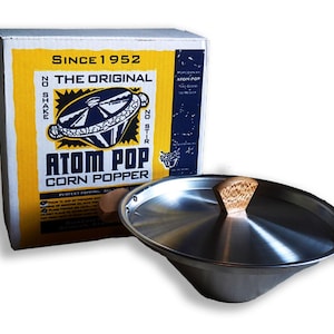May include: A silver metal popcorn popper with a wooden lid and handles. The popper is in front of a yellow box with the text "Since 1952 The Original Atom Pop Corn Popper" printed on it.