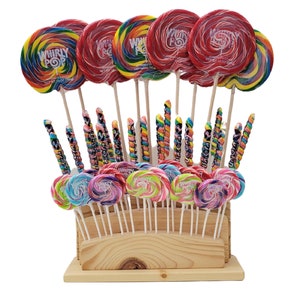 May include: A wooden display case filled with various colorful lollipops. The lollipops are round and swirled with multiple colors, some with the text "Whirly Pop". The display includes a variety of sizes and shapes, including long, twisted candy sticks.