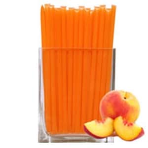 May include: A glass jar filled with a bundle of orange honey straws, with three peach slices on the table in front of the jar.
