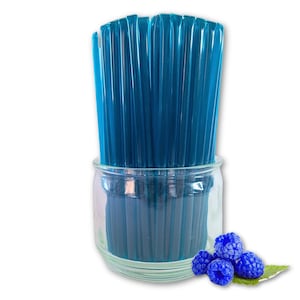 May include: A collection of blue straws in a clear glass jar, with a few blue raspberries on a green leaf. The straws are a vibrant blue color and appear to be made of a transparent material.