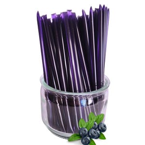 May include: A clear glass jar filled with numerous purple honey sticks. Fresh blueberries and green leaves are arranged at the base of the jar. The honey sticks are a vibrant purple color, suggesting a blueberry flavor.