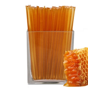 May include: A glass jar filled with honey sticks, a honeycomb with honey dripping from it, and a white background.
