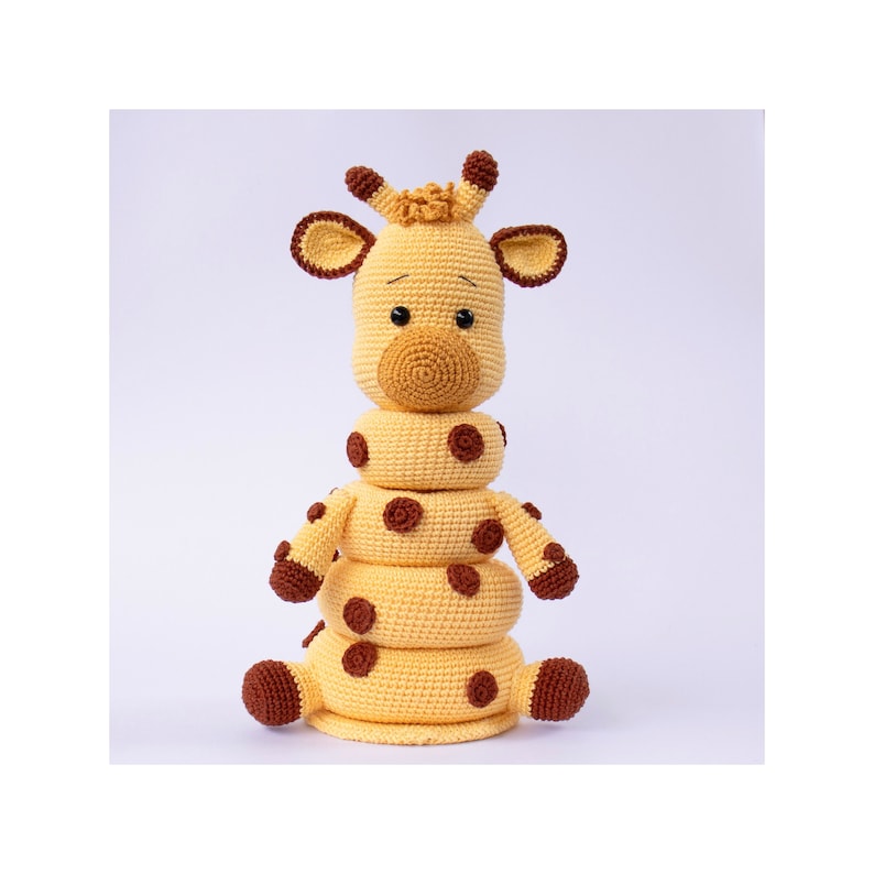 May include: A crocheted giraffe toy with brown spots and a stack of rings for a baby to play with.