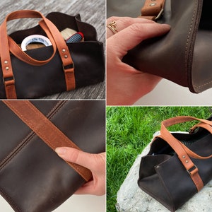 Pode incluir: Uma bolsa de ferramentas de couro castanho escuro com duas al&ccedil;as de couro castanho claro fixadas com rebites de metal. A bolsa tem uma base retangular, design aberto no topo, costuras vis&iacute;veis nas bordas e um acabamento fosco e liso.