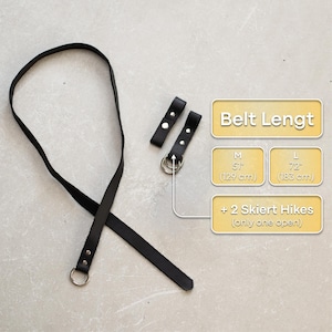 May include: Black leather belt with two metal belt loops and two metal rings. The belt is 51 inches (129 cm) long. The belt is shown with two leather belt loops, each with a metal ring. The text "Belt Lengt" is shown in a yellow box. The text "M 51" (129 cm) is shown in a yellow box. The text "L 72" (183 cm) is shown in a yellow box. The text "+ 2 Skiert Hikes (only one open)" is shown in a yellow box.