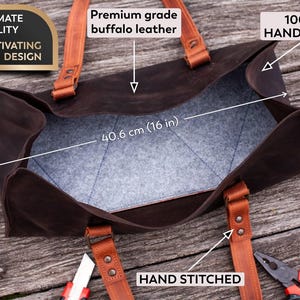 Pode incluir: Uma bolsa de couro de b&uacute;falo marrom escuro com al&ccedil;as de couro marrom claro e interior de feltro cinza. A bolsa mede 40,6 cm de comprimento e 17,8 cm de largura. O texto na imagem inclui Premium grade buffalo leather, 100% HANDMADE e HAND STITCHED.