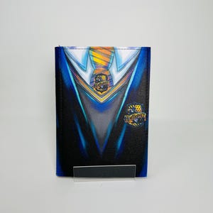 May include: A black and blue wallet with a school uniform design, including a yellow and black crest and the word "Hufflepuff". The wallet is presented on a clear stand.
