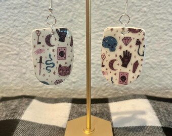 不気味なハロウィーンのダングルイヤリング。黒猫、短剣、邪眼、カボチャ