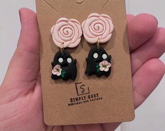 不気味なハロウィンのダングルイヤリング。ピンクの花をつけた黒い幽霊。