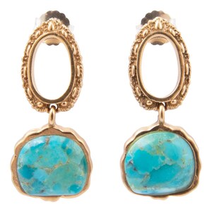 May include: A pair of gold-toned drop earrings featuring an oval-shaped top with a textured, beaded border. Each earring suspends a smooth, irregular, rounded turquoise stone set within a scalloped gold-toned metal frame with a post back.