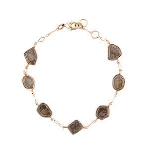 May include: A gold chain bracelet with seven irregularly shaped brown stones. The bracelet has a lobster clasp closure.