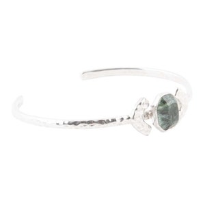 May include: Silver hammered bangle bracelet with a green gemstone set in a silver geometric design.
