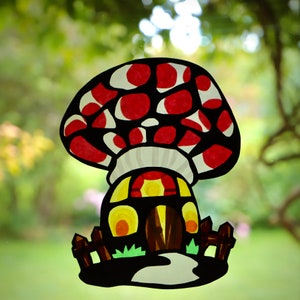 May include: A red and white mushroom shaped house with a yellow door and windows. The mushroom is surrounded by green grass and black fences.
