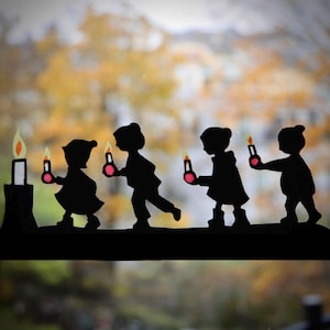 Peut inclure: Silhouette de cinq enfants tenant des bougies, chacune avec une flamme rose, sur un fond flou de feuillage d'automne.