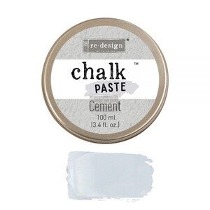 May include: A round tin container of Re-Design with Prima Chalk Paste in Cement color. The container is silver with black lettering and a small image of a building. The paste is a light gray color.